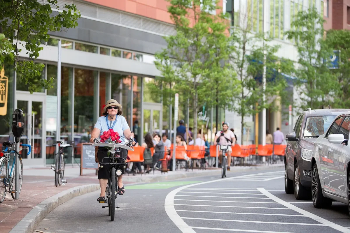 Commuter riding in a city bike lane near a transit stop, illustrating car-free city living tips