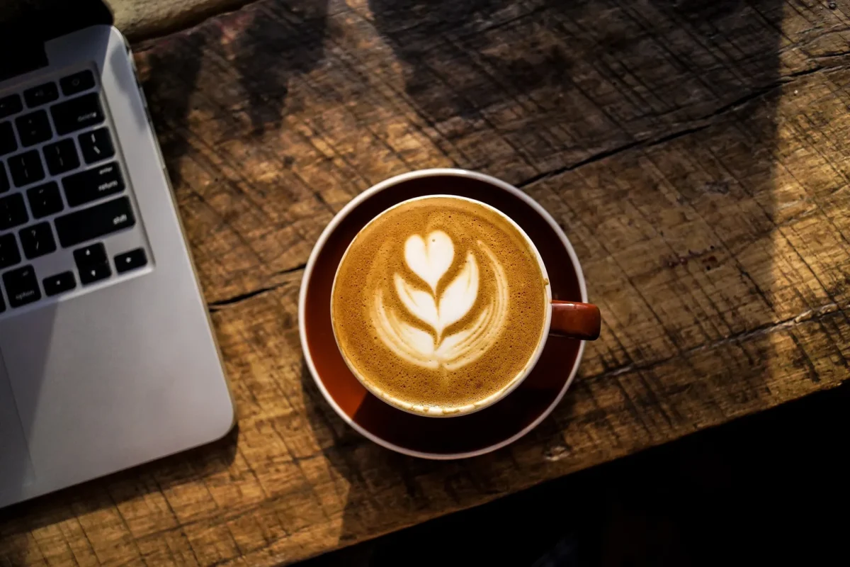 Laptop and latte on a wooden table in one of the best coffee shops for remote work